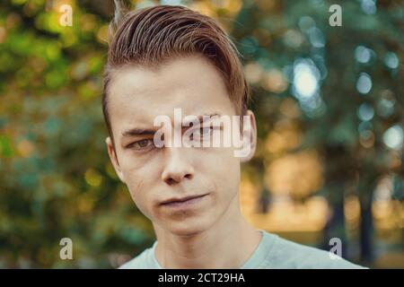 Portrait d'un jeune homme blanc sérieux et attrayant de 23 ans lors de la marche dans le parc public le jour. Banque D'Images