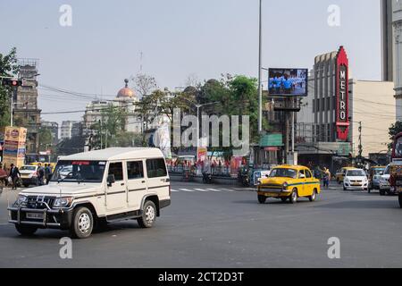 Kolkata, Inde - 1er février 2020 : des personnes non identifiées se promène sur le côté de la rue à un carrefour, tandis que les bus et les voitures passent devant dans la circulation Banque D'Images