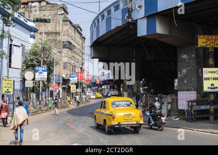 Kolkata, Inde - 1er février 2020 : des personnes non identifiées se promène dans la rue en taxi jaune traditionnel et en moto, sous Maa Flyover Banque D'Images