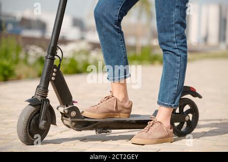 Vue latérale des jambes d'une jeune femme d'affaires en daim beige chaussures et jeans bleus Banque D'Images