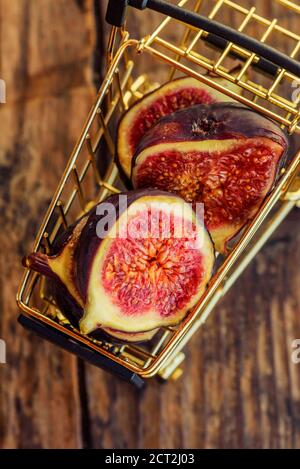 Figues fraîches . Belles figues bleues violettes. Figues dans le chariot d'épicerie sur fond de bois Banque D'Images