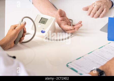 Main du médecin appuyant sur la pompe du tonomètre tout en mesurant le sang pression Banque D'Images