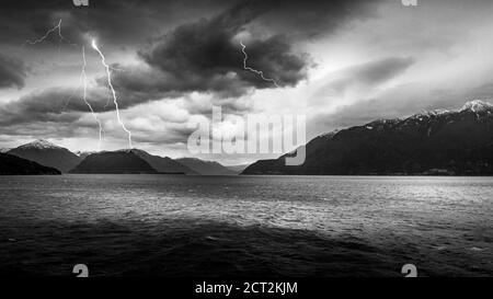 Noir et blanc la photo des nuages sombres et de la foudre frappe dans le cours d'une traversée en ferry entre Horseshoe Bay et Sechelt en Colombie-Britannique, Canada Banque D'Images