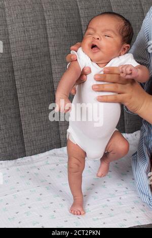 nouveau-né de 3 semaines, pas de réflexe, mouvement de marche lorsqu'il est tenu debout avec le poids sur les pieds Banque D'Images