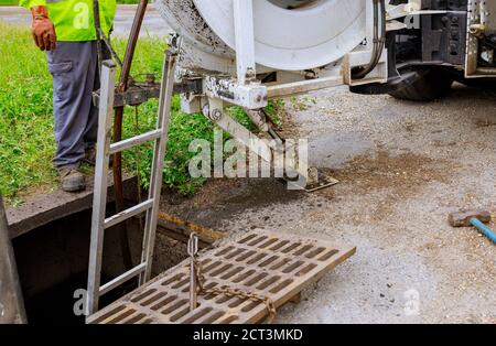 Les travailleurs du nettoyage des eaux usées ont un équipement avec un égout dans une rue de ville sur un camion industriel Banque D'Images