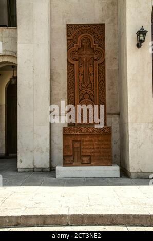 Khachkar en pierre avec une croix sculptée avec des paons, un motif végétal, des grenades et des raisins, ornement de cercle installé sur le côté gauche du mur environ Banque D'Images