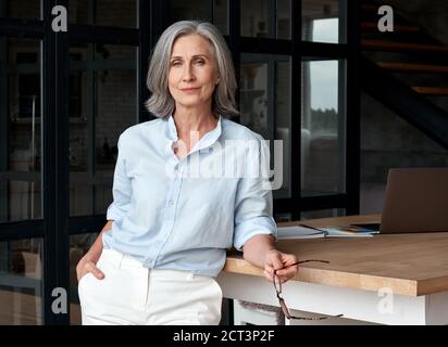 Femme d'âge moyen pleine d'assurance debout au bureau, portrait. Banque D'Images