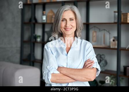 Souriante confiante femme d'âge moyen debout bras croisés dans le bureau, portrait. Banque D'Images