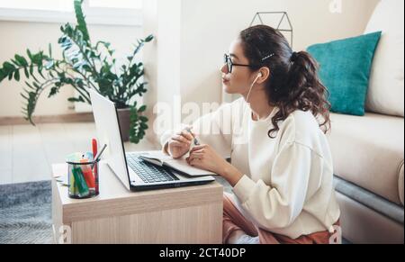Attentionnée femme caucasienne avec des lunettes a des leçons en ligne pendant utilisation d'un casque et d'un ordinateur portable Banque D'Images