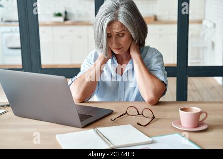 Fatiguée stressée vieille femme d'affaires d'âge moyen souffrant de douleurs au cou. Banque D'Images