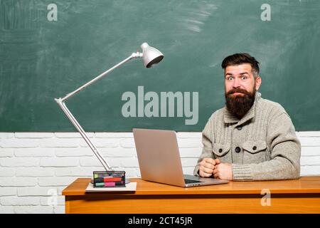 Travail d'enseignant - profession et concept d'apprentissage. Journée des enseignants. Tuteur. Jeune enseignant près du tableau noir dans la salle de classe de l'école. Banque D'Images