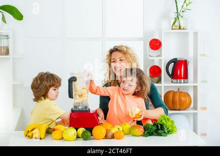 Mère et ses deux enfants mélangeant cocktail avec fruits et boisson smoothie, concept de fête des mères, Banque D'Images