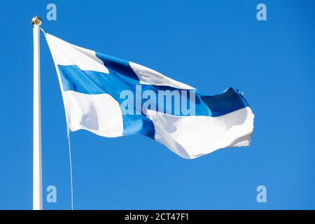 Le drapeau de la Finlande fait des vagues dans le vent contre le bleu ciel d'été Banque D'Images