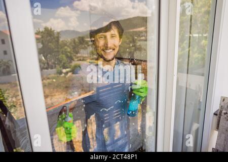 Un jeune homme nettoyant la fenêtre avec un nettoyant pour vitres Banque D'Images