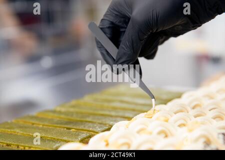 Le chef pâtissier tient des pinces à noix et décorera les gâteaux avant de servir au restaurant. Concept de haute cuisine Banque D'Images