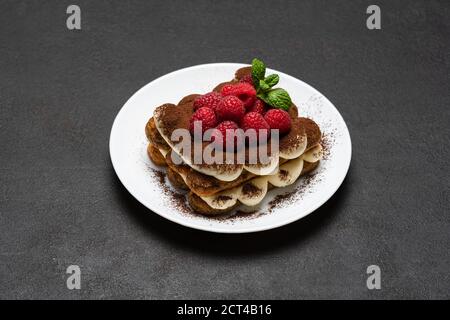 Portion de dessert tiramisu classique avec framboises sur béton foncé arrière-plan Banque D'Images