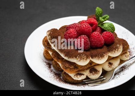 Portion de dessert tiramisu classique avec framboises sur béton foncé arrière-plan Banque D'Images