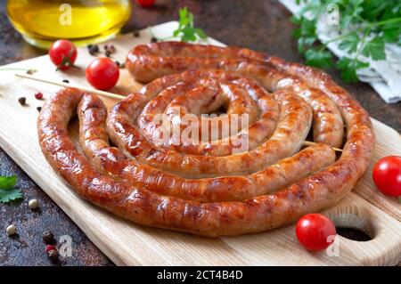 De délicieuses saucisses maison, des rondelles de brochettes cuites au four et des tomates cerises. En-cas Oktoberfest. Plat de pique-nique d'été Banque D'Images