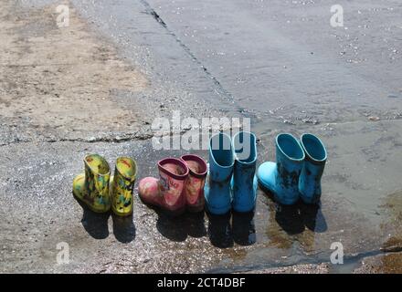 Quatre paires de bottes en caoutchouc pour enfants sur un bateau humide rampe Banque D'Images