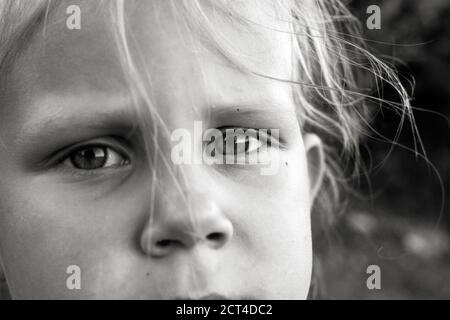 Gros plan photo en noir et blanc d'un enfant caucasien mignon. Moments d'enfance. Portrait, visage et yeux de l'enfant en gros plan Banque D'Images