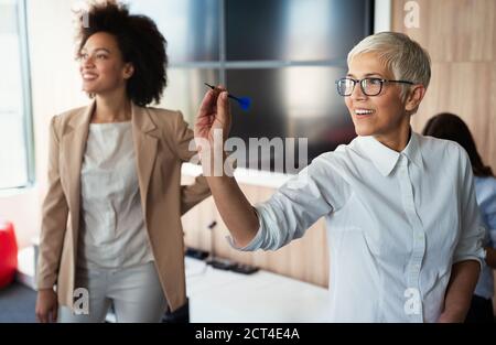 Des gens d'affaires heureux construisent des équipes et s'amusent, jouant aux fléchettes pendant la pause au bureau Banque D'Images