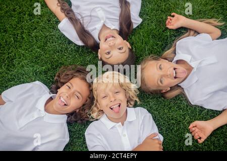 Enfants en blanc couché sur l'herbe et souriant Banque D'Images