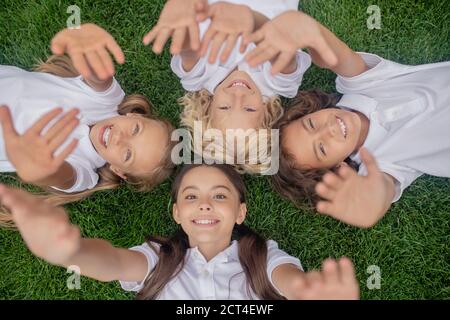 Enfants en blanc, allongé sur l'herbe et étirant les mains Banque D'Images