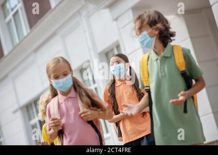 Écoliers dans des masques protecteurs ayant conflit dans la cour d'école Banque D'Images