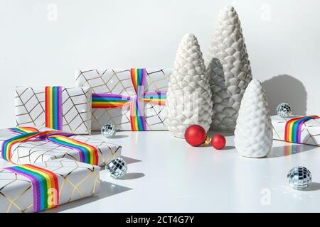 Cadeaux de Noël avec ruban arc-en-ciel aux couleurs du drapeau de la communauté LGBT. Décorations de Noël, boules, sapins en céramique, boîtes-cadeaux emballées. Banque D'Images