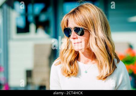 Portrait en gros plan d'une femme d'âge moyen portant des lunettes de soleil tout en se relaxant dans le jardin à la maison. Banque D'Images