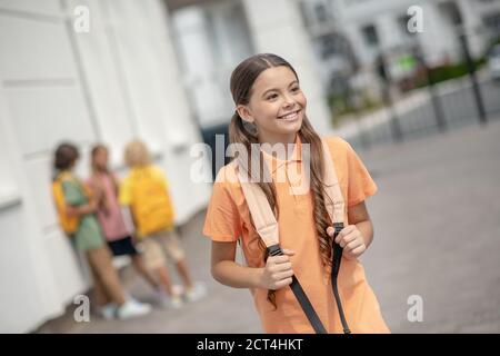 Jolie fille en chemise orange souriant joliment et à l'air gai Banque D'Images