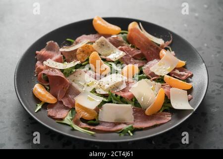 Salade avec prosciutto, tangerines et fromage vintage sur plaque noire, peu profond foyer Banque D'Images