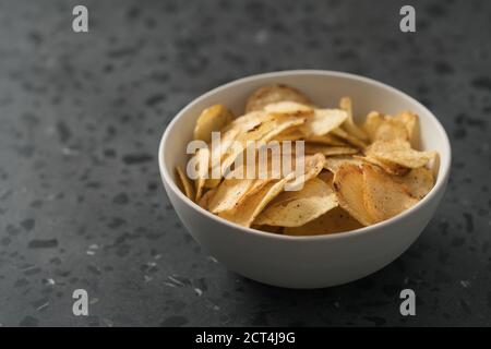 Pomme de terre légèrement arrosée de poivre noir dans un bol blanc sur fond de béton avec espace de copie, peu profond foyer Banque D'Images