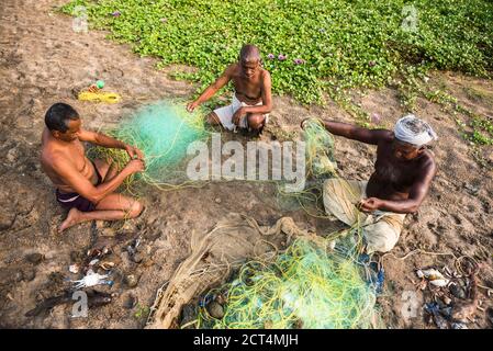 Pêcheurs qui font des filets de pêche à la plage de Kappil, Varkala, Kerala, Inde Banque D'Images