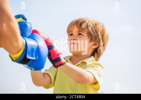 Le père forme sa boxe de fils. Petit garçon faisant de l'exercice de boxings avec grand-père. Petit sportif de garçon à l'entraînement de boxe avec entraîneur. Homme sportif Banque D'Images