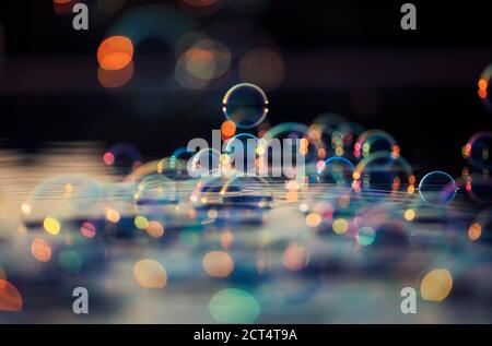 superbe fond coloré avec des bulles de savon brillantes qui survolent le eau et réfléchie dans les rayons du coucher du soleil Banque D'Images