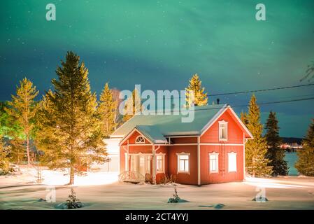 aurores boréales (aurora borealis) au-dessus des maisons scandanaviennes traditionnelles dans le village d'Akaslompolo, une petite ville de la Laponie finlandaise, à l'intérieur du cercle arctique en Finlande Banque D'Images