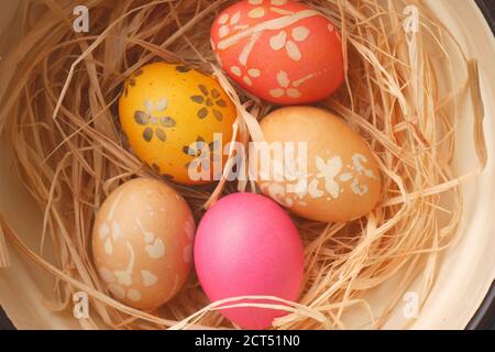 Peint des oeufs de Pâques sur un lit de paille dans un bol Banque D'Images