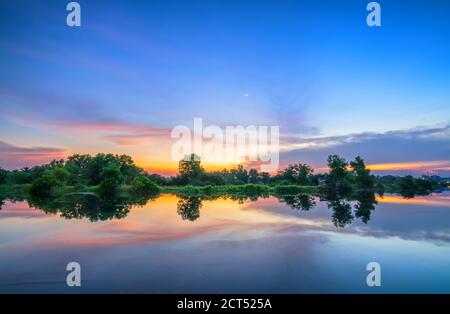 Le coucher de soleil sur la rive reflète le calme fond dedans la campagne Banque D'Images