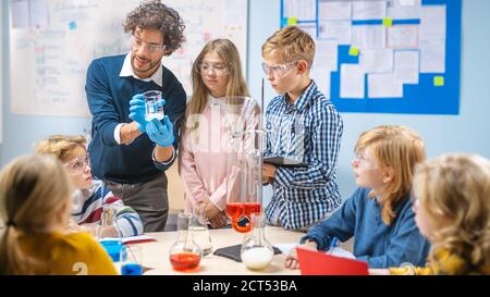 École élémentaire de sciences en classe: Un professeur enthousiaste explique la chimie à divers groupes d'enfants, leur montre comment mélanger les produits chimiques dans les béchers Banque D'Images