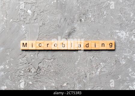 Mot Microblading écrit sur un bloc de bois. Microblading texte sur la table de ciment pour votre conception, concept. Banque D'Images