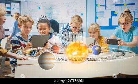 Groupe d'enfants d'école en classe de sciences utiliser des tablettes numériques avec le logiciel de réalité augmentée, regardant l'animation éducative 3D de solaire Banque D'Images