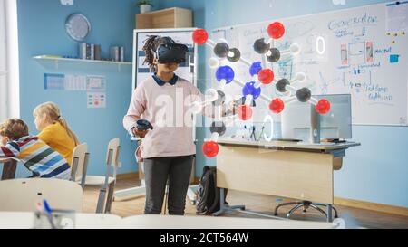 Mignon Girl porte un casque de réalité augmentée et utilise des contrôleurs interagit avec 3D Molecule. Cours de science futuriste pour les enfants en apprentissage Banque D'Images