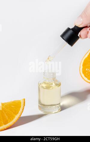 Huile ou essence cosmétique en flacon en verre ouvert et pipette dans la main de la femme sur un fond blanc isolé. Protection contre l'âge. Gros plan. Format vertical. Banque D'Images