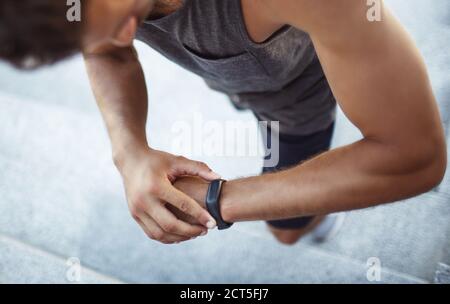 Jeune homme s'exerçant à l'extérieur. Vue d'un homme puissant et puissant qui vérifie son résultat sur le tracker d'activité de sa main. Suivi du temps. Marcher sur les marches. Banque D'Images