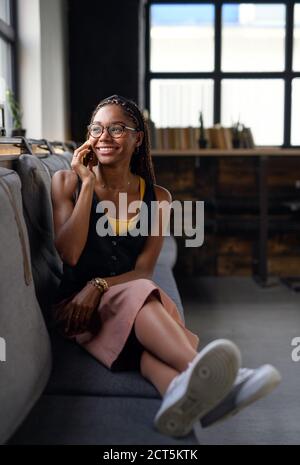 Portrait d'une jeune femme d'affaires à l'intérieur du bureau, à l'aide d'un smartphone. Banque D'Images