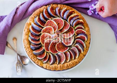 Une femme qui a mis en place une tarte aux figues colorée avec du glaçage sucre sur la table de cuisine Banque D'Images