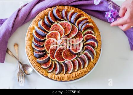 Une femme qui a mis en place une tarte aux figues colorée avec du glaçage sucre sur la table de cuisine Banque D'Images