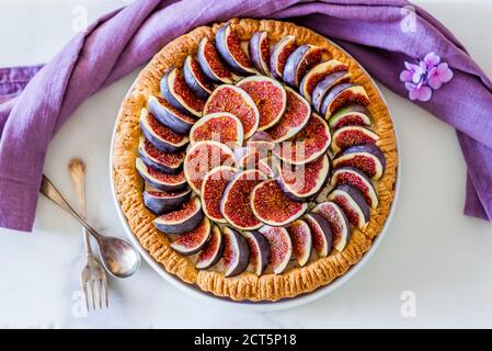 Une femme qui a mis en place une tarte aux figues colorée avec du glaçage sucre sur la table de cuisine Banque D'Images