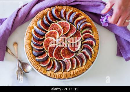 Une femme qui a mis en place une tarte aux figues colorée avec du glaçage sucre sur la table de cuisine Banque D'Images